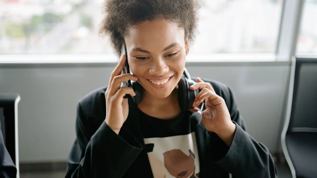 A smiling insurance agent answering a lead on the phone with a headset